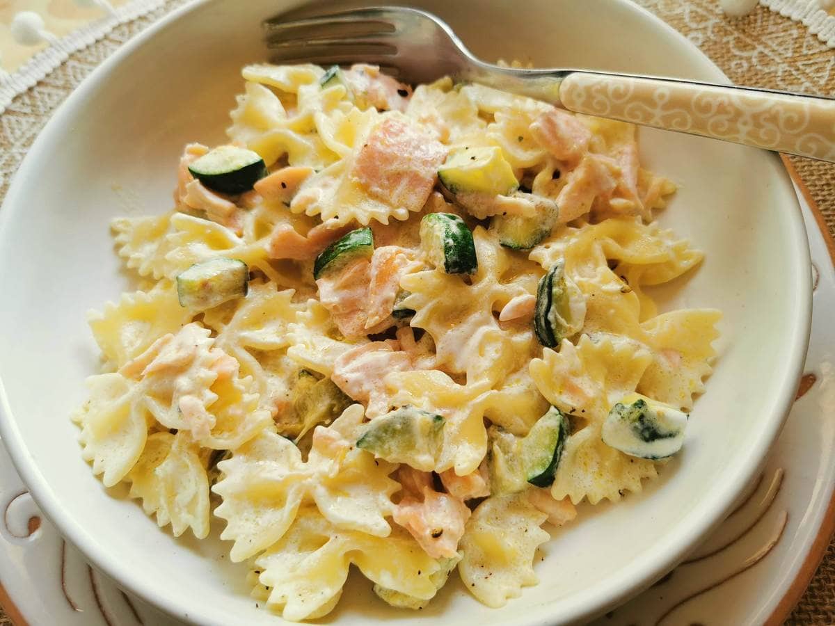 Farfalle pasta with smoked salmon and zucchini in white bowl.