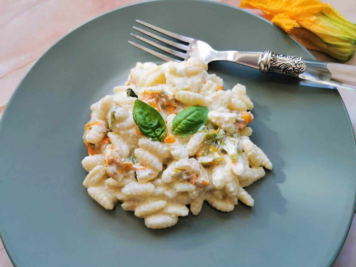 Malloreddus pasta with zucchini flowers, ricotta and saffron on a plate.